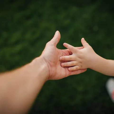A parent's hand holding a child's hand outdoors
